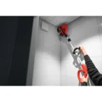 Utilisation de la brosse électrique SCRUBBY CAS avec manche télescopique pour nettoyer les angles et les surfaces carrelées en hauteur.